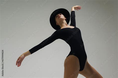Young Ballerina In A Black Bodysuit Shows Ballet Steps In Motion