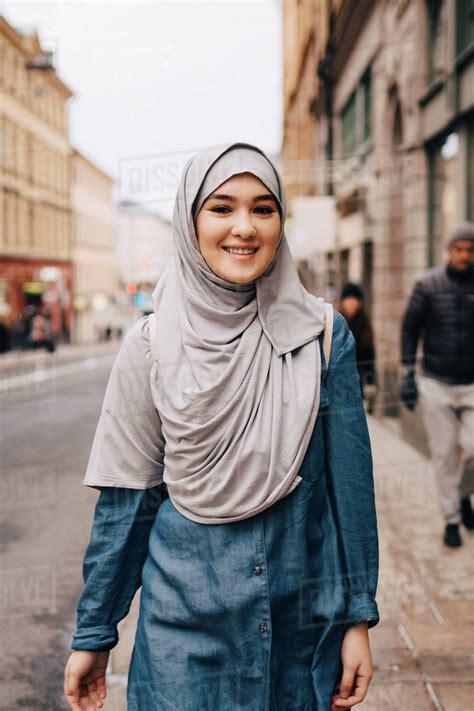 Portrait Of Smiling Young Muslim Woman Wearing Hijab Walking On