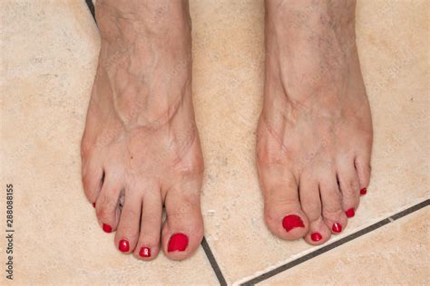 A Close Up And Top View On The Bare Feet Of An Older Lady With Painted Red Toe Nails Showing