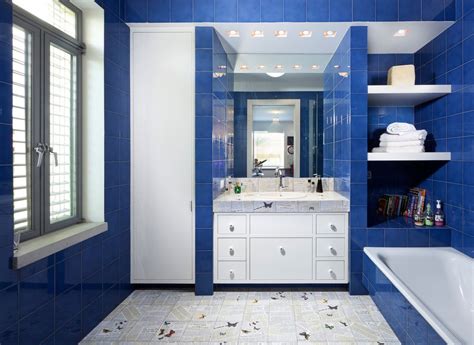 A rich shade of blue coats the vanity and round mirror in this transitional bathroom. Blue bathroom ideas. Design, décor, and accessories