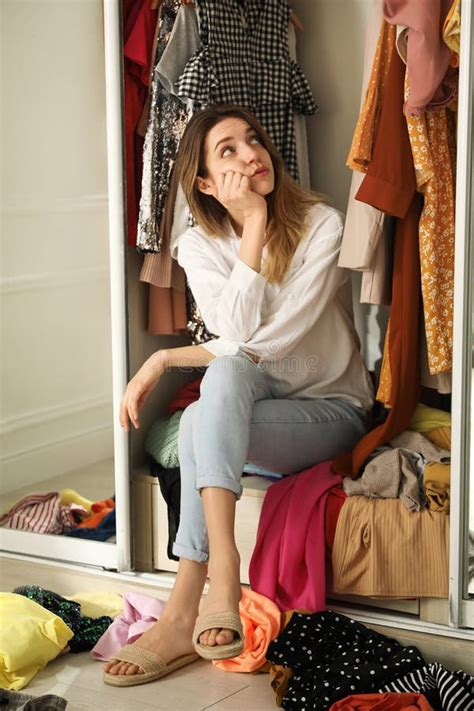 Young Woman Sitting In Wardrobe With Different Clothes Indoors Fast Fashion Concept Stock Image