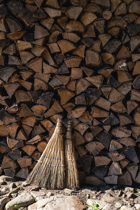 Two Brooms Against Stacked Firewood By Stocksy Contributor Pixel