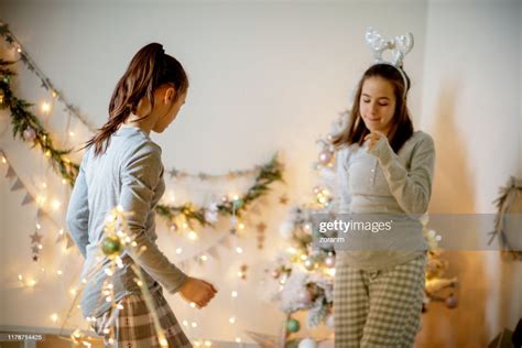 Two Teenage Girls Dancing In Pajamas By The Christmas Tree High Res