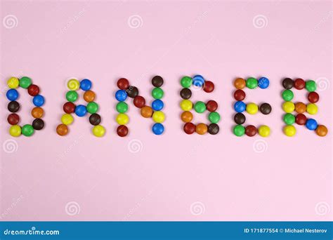 peligro de palabras de caramelos multicolores sobre fondo rosa foto de archivo imagen de sano