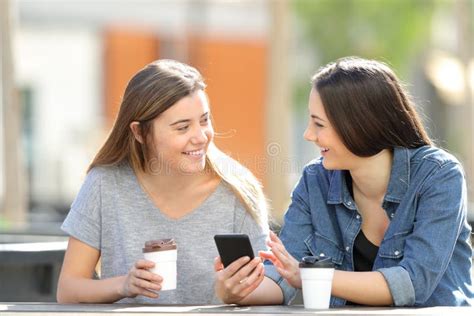 Two Friends Talking About Phone Content In A Park Stock Image Image