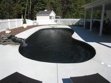 A Pool With Water Flowing From It In Front Of A White Picket Fence And
