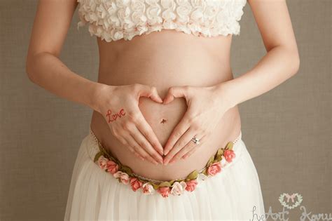 妊婦さんがお腹に両手でハートを作っているおしゃれなマタニティフォト。 マタニティフォトの撮影事例