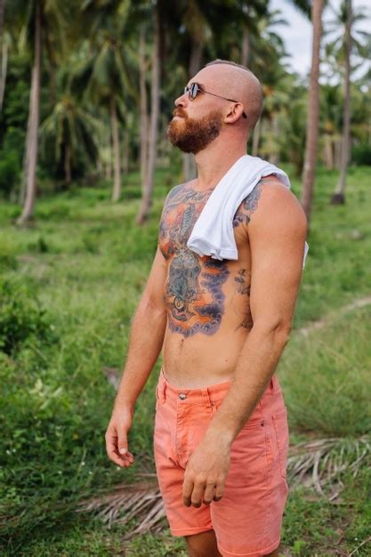 셔츠없이 정글 열대 필드에 문신을 한 강한 남자 무료 사진