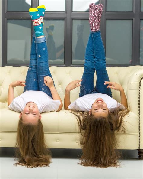 Two Funny Girls Are Lying In The Studio On The Couch Upside Down Stock