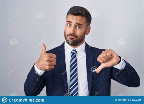 Handsome Hispanic Man Wearing Suit And Tie Doing Thumbs Up And Down Disagreement And Agreement