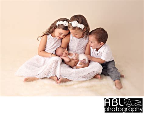 Older Siblings Holding Newborn Baby San Diego Newborn Photographer