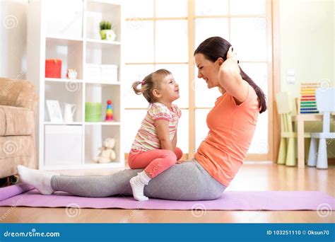 Дочь матери и ребенка приниманнсяый за фитнес йога работает дома Пресса качания ребенк и