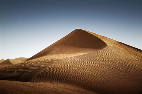 Picture Of A Tall Textured Sand Dune Standing Against A Clear Blue Sky