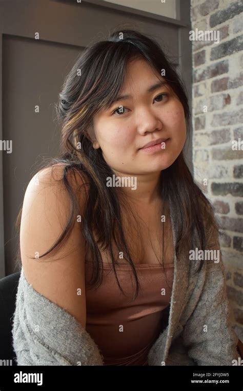 asian american model posing for camera dressed in short dress and sweater legs crossed hand