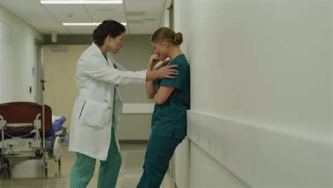 doctor comforting crying nurse in hospital corridor stock video footage dissolve