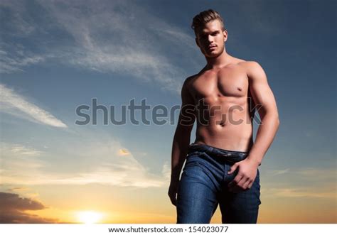Young Topless Man Outdoor Looking Down At The Camera With The Sunset Behind