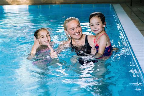 母亲带着两个女儿在室内游泳池玩乐女孩正在水上公园休息幼儿游泳学校概念友好的家庭体育暑假高清图片下载 正版图片506719669 摄图网