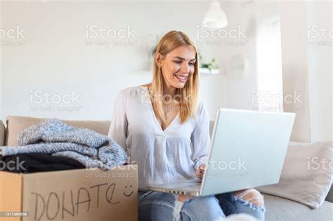 Happy Young Woman Sit On Couch Stuck Clothes In Donation Box At Home