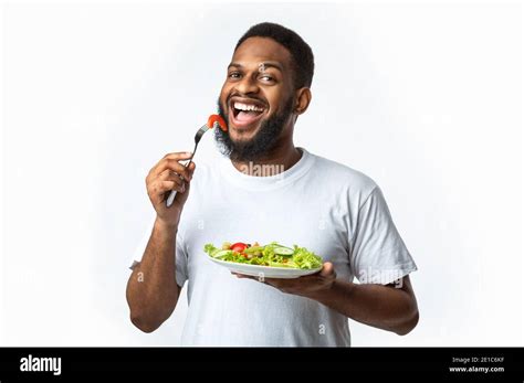Happy African American Man Eating Healthy Salad Standing In Studio
