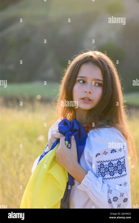 una adolescente triste sostiene una bandera ucraniana en su pecho la niña está vestida con ropa