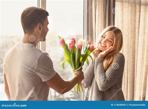 Romantic Young Man Presenting Flowers To His Girlfriend At Home Stock Image Image Of Interior
