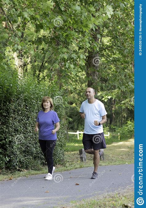 Old Mature Couple Of Man And Woman Running Together In The City Park To
