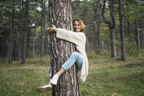 Woman Hugging Tree In Forest Stock Photo