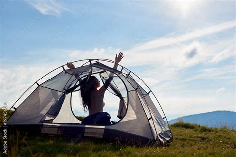 Foto Stock Back View Of Silhouette Of Attractive Naked Woman Camper Sitting In Tent With Lifting