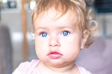Un Bebé Con Ojos Azules Está Mirando A La Cámara Foto Premium