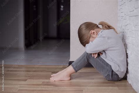 Sad Little Child Girl Sitting On Floor In Corner At Home Stock Photo