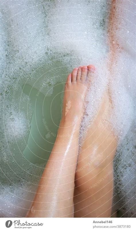 women s legs in the bathtub bathing with bubble bath foam top view relaxtion beauty spa