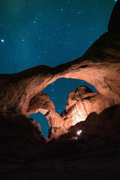 The Stars Are Shining In The Night Sky Above An Arch Shaped Like A Rock