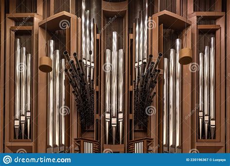 Brass Pipes Of Organ At Wooden Wall In Light Catholic Church Stock