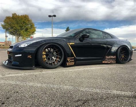 A Black Sports Car With Gold Lettering On Its Side Parked In A Parking Lot