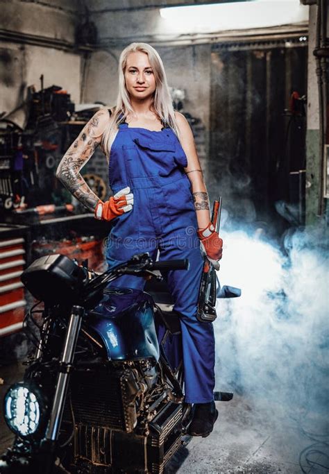 Beautiful Female Mechanic With Tattooed Hands In Work Overalls Posing
