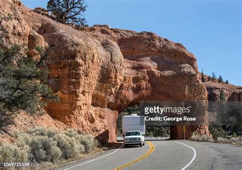 A Recreational Vehicle Drives Through A Natural Arch In Red Canyon On