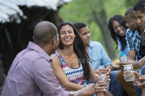 Cheerful Young Friends Having Drinks Talking And Laughing In