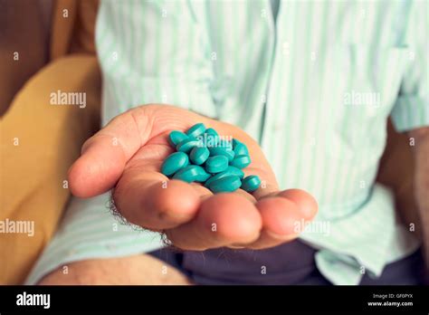 Closeup Of An Old Caucasian Man With A Pile Of Blue Pills In His Hand