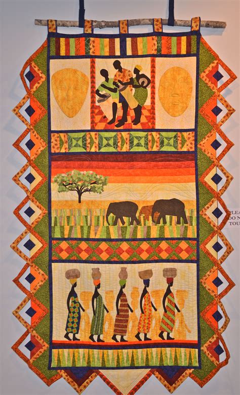 An African Quilt Hanging On A Wall With Elephants And People In The