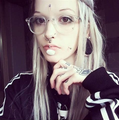 A Woman With Glasses And Piercings On Her Nose Is Posing For The Camera