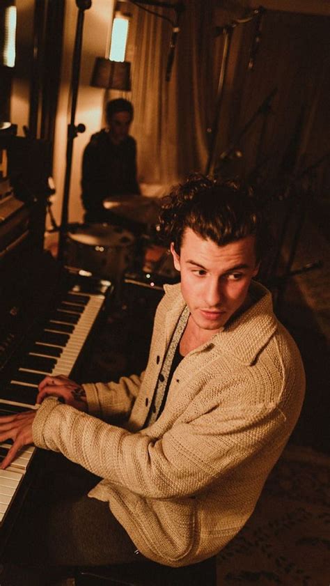 A Man Sitting At A Piano With His Hands On The Keyboard And Another