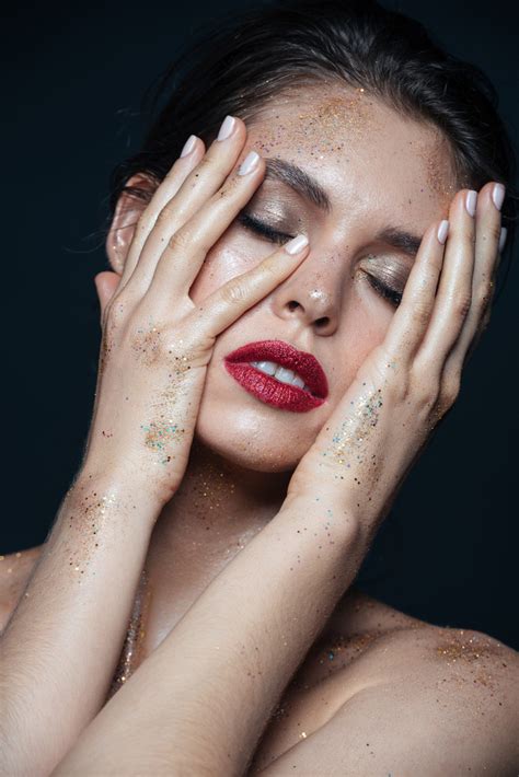 Beauty Portrait Of Tender Young Woman With Glitter Makeup Touching Her Face With Both Hands Over