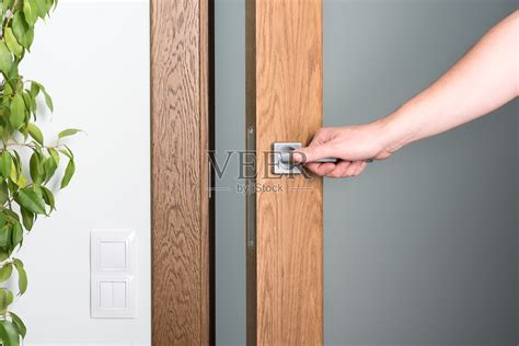 开门。一个男人的手在门把手上。深色木材和浅色室内照片摄影图片 id 327328726 veer图库