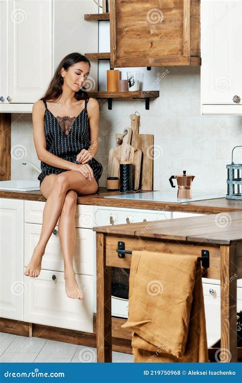 African American Woman Sitting On The Kitchen Counter And Looking At