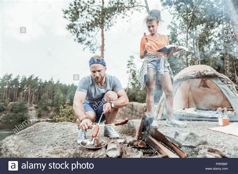Bearded Blonde Haired Man Broiling Some Sausages For Picnic With