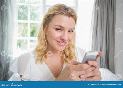 Pretty Blonde Sitting On Bed Texting On The Phone Stock Image Image