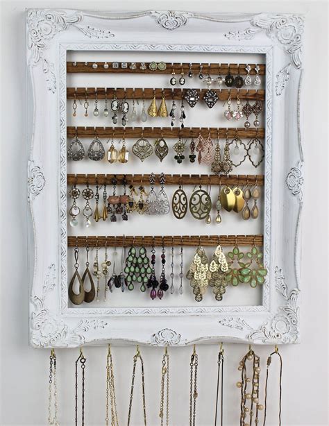 A White Frame Holds Several Pairs Of Earrings And Earring Hooks On A