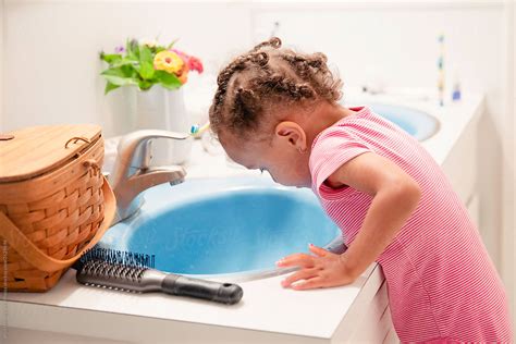 Toddler Brushing Her Teeth And Spitting In The Sink By Stocksy