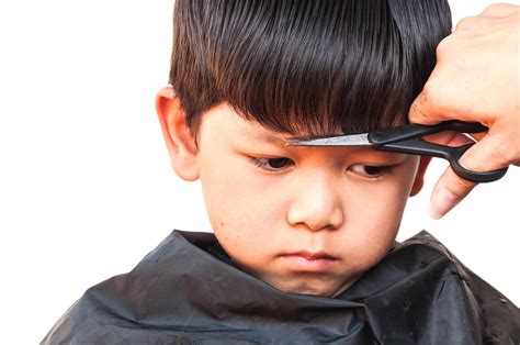 A Boy Is Cut His Hair By Hair Dresser Over White Background Focus At