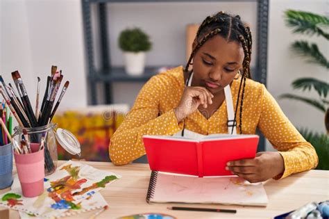 African American Woman Artist Reading Book At Art Studio Stock Photo